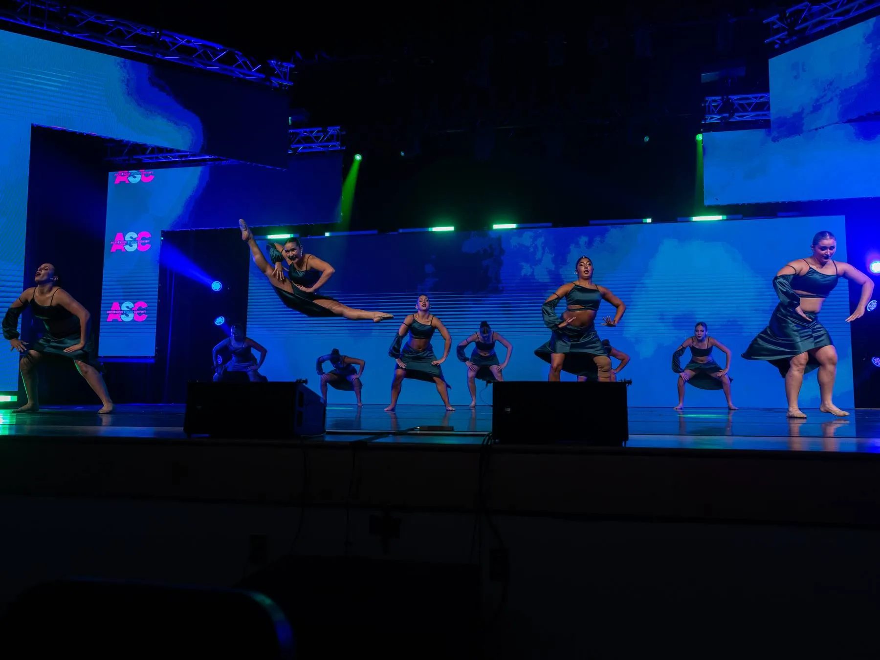 The Studio Company in black satin, one dancer suspended in a mid-air split